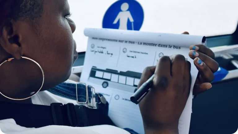 Une usagère remplit à la main un questionnaire sur ses impressions lors de la montée dans le bus.